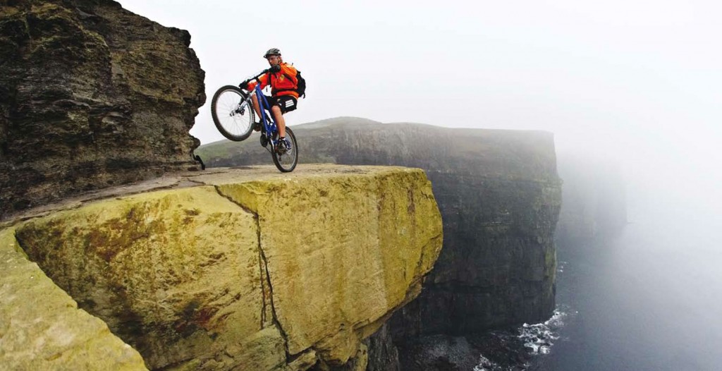 riding a wheelie next to a cliff