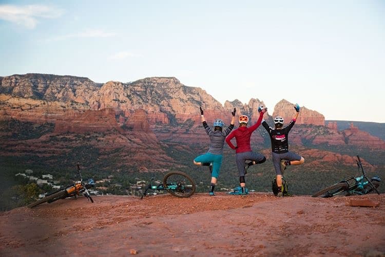 Mountain bikers doing yoga pose while looking at a view