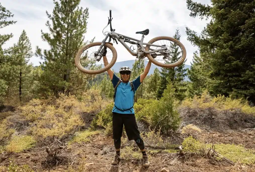 Man in blue shirt holding his mountain bike above his head