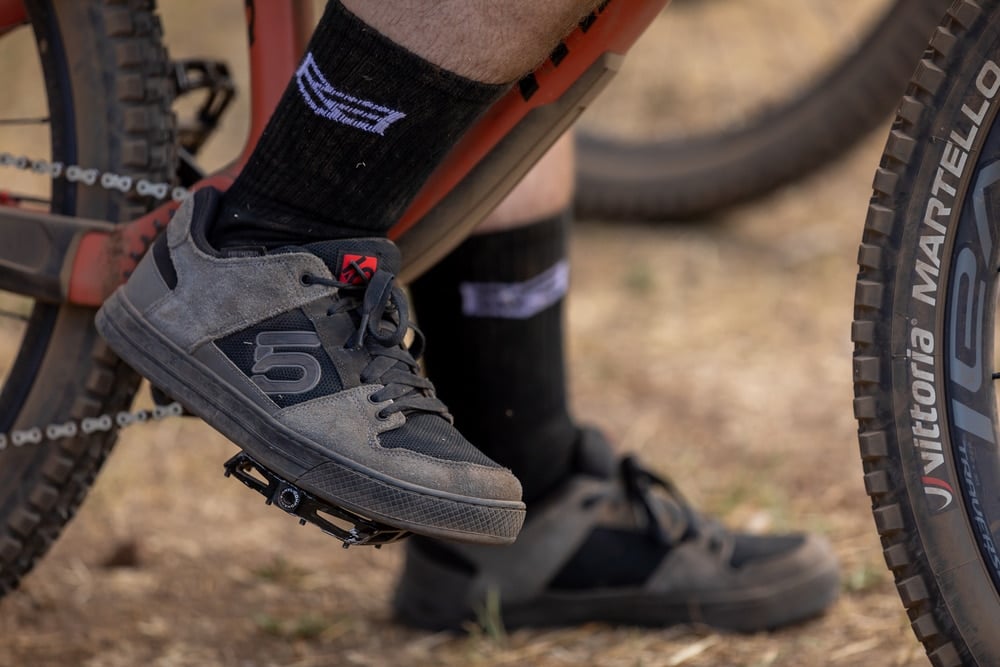 Man wearing mountain bike shoes standing on a pedal