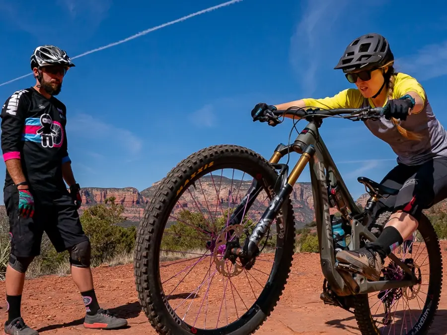 Ninja coach helping a rider lift her front wheel on red dirt